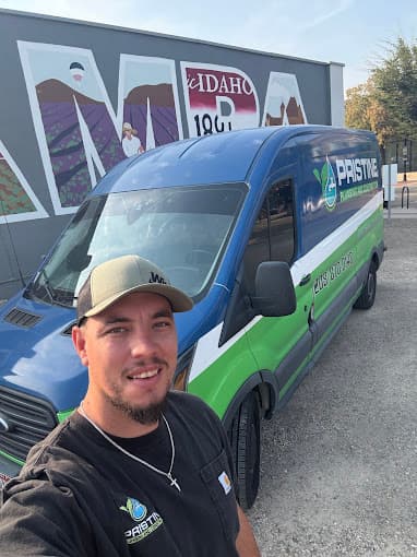 A Pristine Plumbing technician with a company van in front of the Nampa, Idaho mural