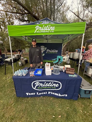 The Pristine Plumbing stand at a community event, under a branded canopy