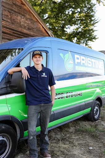 A Pristine Plumbing technician leaning against the door of a branded service van