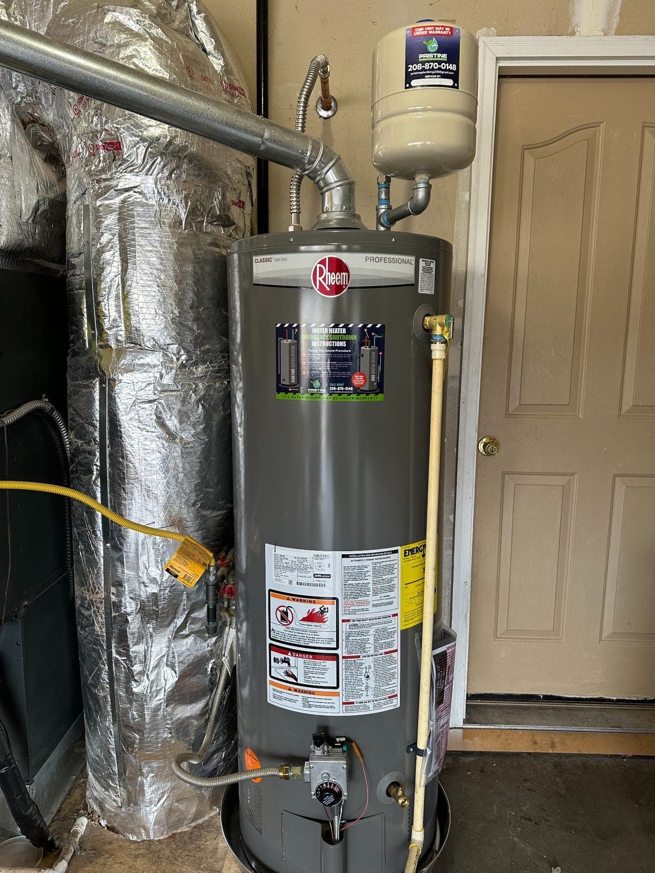 A newly installed gas water heater with expansion tank and a Pristine Plumbing service sticker