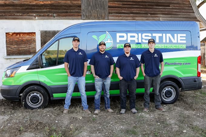 Four Pristine Plumbing technicians standing in front of a branded service van