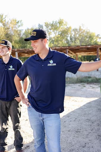 Two Pristine Plumbing technicians in branded polo shirts and caps